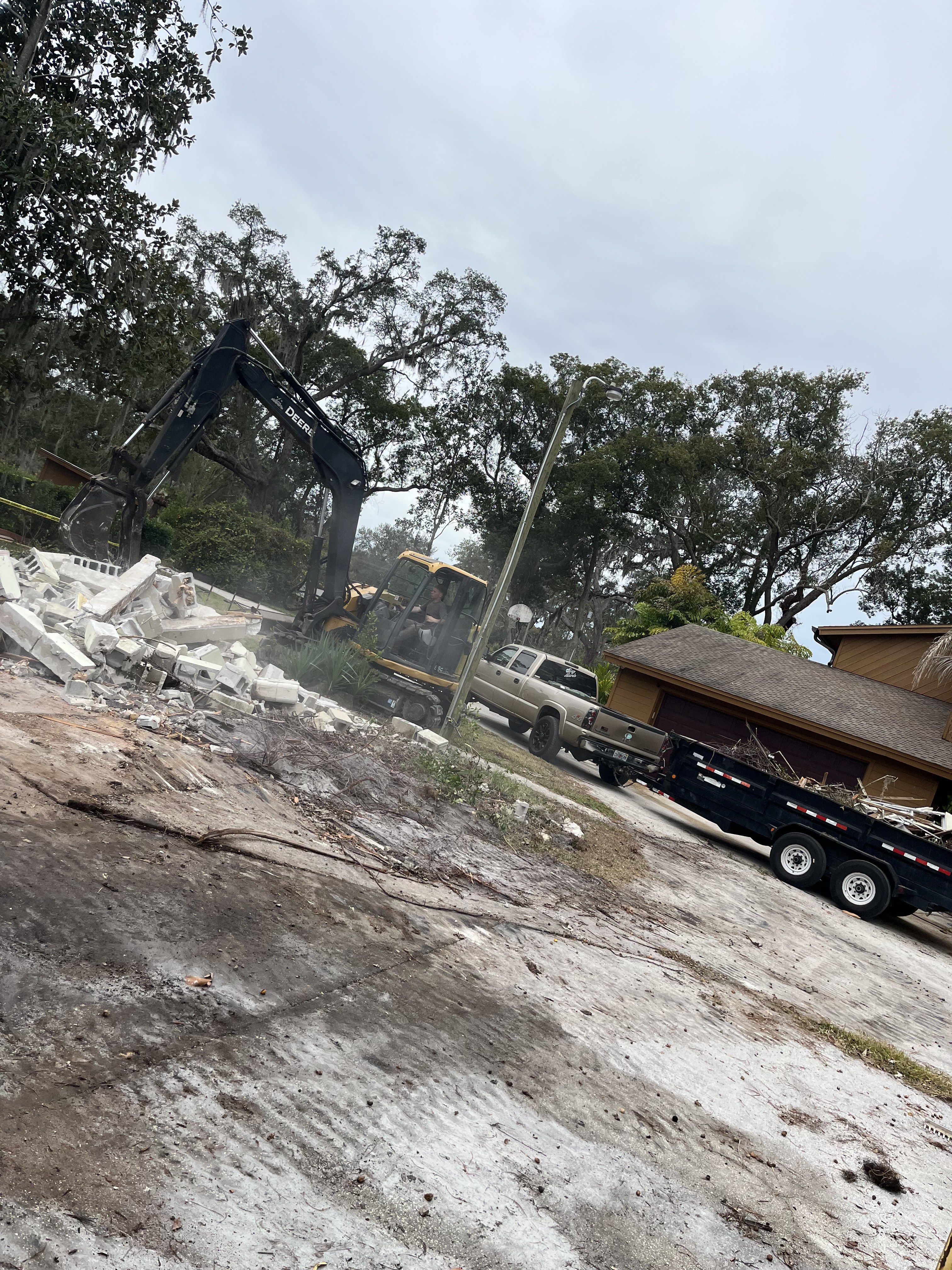 Excavator loading concrete block and demolition debris onto a dump trailer